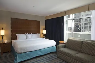 a bedroom with a bed and a couch and a window at Fairfield Inn & Suites by Marriott New York Manhattan/Fifth Avenue in New York