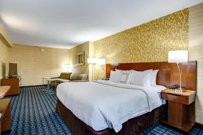 a hotel room with a large bed and a chair at Fairfield Inn & Suites by Marriott Springfield Holyoke in Holyoke