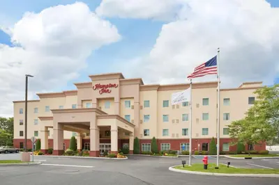 a hotel with an american flag in front of it at Hampton Inn Kingston in Kingston
