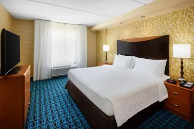 a hotel room with a bed and a flat screen tv at Fairfield Inn and Suites by Marriott Plainville in Plainville