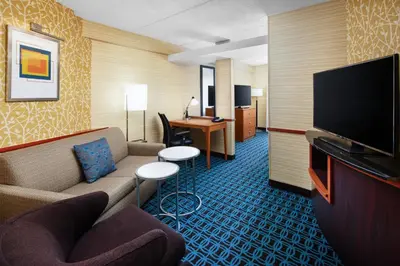 a hotel room with a couch and a flat screen tv at Fairfield Inn and Suites by Marriott Plainville in Plainville