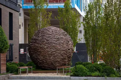 a large sculpture in front of a building with two benches at The Lloyd Stamford, Tapestry Collection by Hilton in Stamford