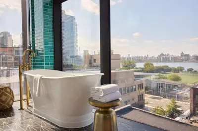 a bath tub in a bathroom with a view of a city at Arlo Williamsburg in Brooklyn
