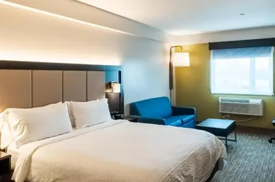 a hotel room with a bed and a blue chair at Holiday Inn Express Maspeth by IHG in Queens