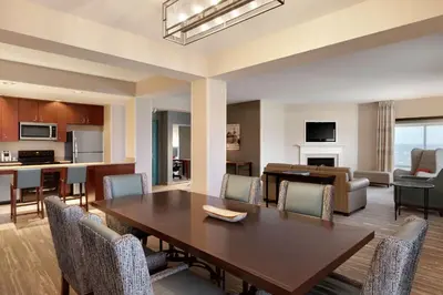 a dining room and living room with a table and chairs at Hilton Garden Inn Troy in Troy
