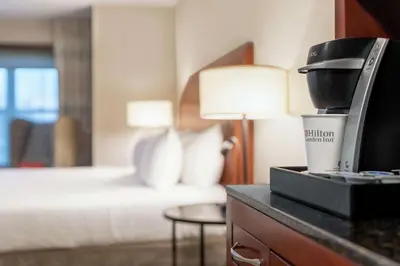 a hotel room with a bed and a coffee maker on a counter at Hilton Garden Inn Troy in Troy