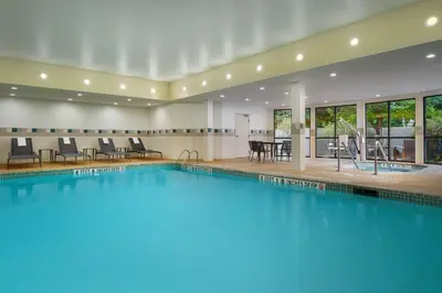 a swimming pool in a hotel with chairs and tables at Courtyard by Marriott Kingston in Kingston