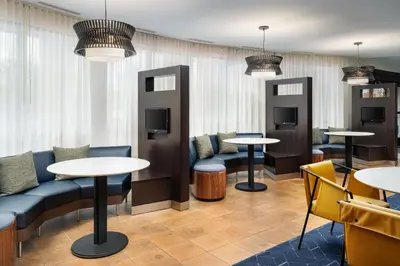 a waiting room with tables and chairs and pendant lights at Courtyard by Marriott Kingston in Kingston