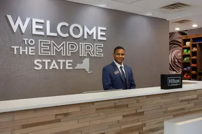a man in a suit standing behind a counter at Hampton Inn & Suites Yonkers in Yonkers