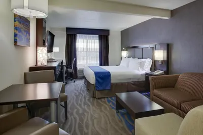 a hotel room with a bed and a living room at Holiday Inn Express Hotel & Suites Meadowlands Area by IHG in Carlstadt