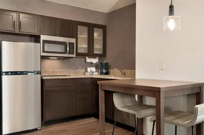 a kitchen with a refrigerator and a table with chairs at Residence Inn by Marriott West Springfield in West Springfield