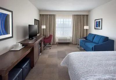a hotel room with a bed and a blue couch at Hampton Inn by Hilton New Paltz, NY in New Paltz
