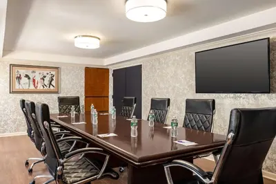 a conference room with a table and chairs and a flat screen tv at Inn at Great Neck in Great Neck