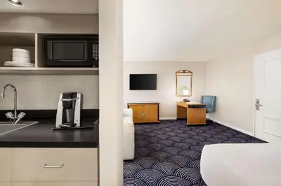 a hotel room with a kitchen and a bathroom at Inn at Great Neck in Great Neck