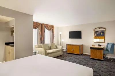 a hotel room with a bed and a living room at Inn at Great Neck in Great Neck