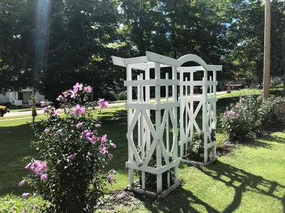 a white structure in a garden with flowers at Stamford Gables Bed and Breakfast in Stamford