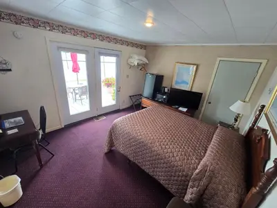 a bedroom with a bed and a television and a window at Lake View Motel in Cooperstown