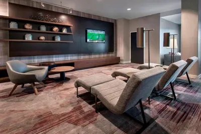 a waiting room with chairs and a tv at Courtyard by Marriott Schenectady at Mohawk Harbor in Schenectady