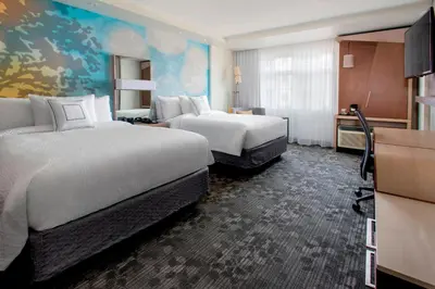 a hotel room with two beds and a tv at Courtyard by Marriott Schenectady at Mohawk Harbor in Schenectady