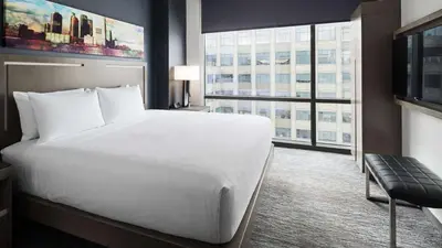 a hotel room with a bed and a large window at Hyatt House Jersey City in Jersey City