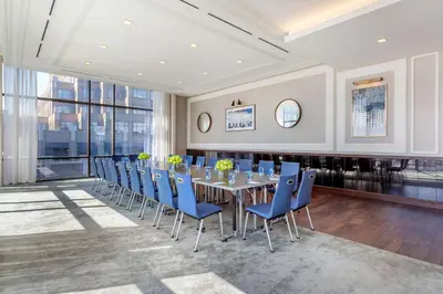 a dining room with a long table and blue chairs at Hyatt House Jersey City in Jersey City