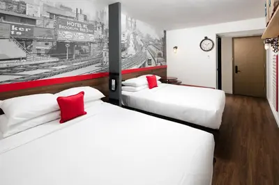 two beds with red pillows in a hotel room at Hotel 1080 in Brooklyn