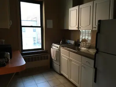a kitchen with white cabinets and a stove and a window at Beauty Near Times Square in New York