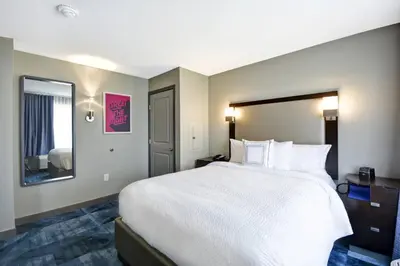 a bedroom with a large white bed and a mirror at TownePlace Suites by Marriott Dover Rockaway in Dover