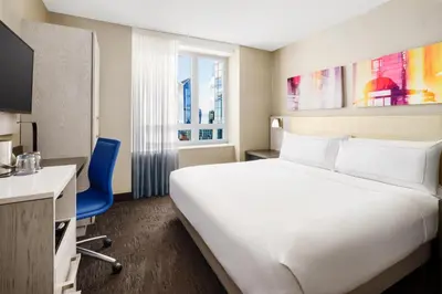 a hotel room with a large white bed and a blue chair at Doubletree By Hilton New York Times Square West in New York