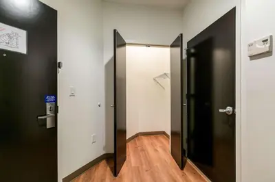 a hallway with a black door and a white room at Feather Factory Hotel in Queens