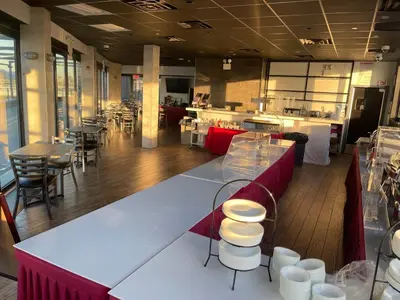 a restaurant with a counter and tables and chairs at Feather Factory Hotel in Queens