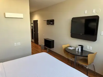 a room with a bed and a table and a tv at Feather Factory Hotel in Queens