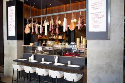 a restaurant with a counter with white chairs and meats at LUMA Hotel - Times Square in New York