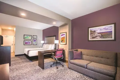 a hotel room with a bed and a desk and a couch at La Quinta Inn & Suites by Wyndham Clifton Park Saratoga Area 1749 Route 9 in Clifton Park