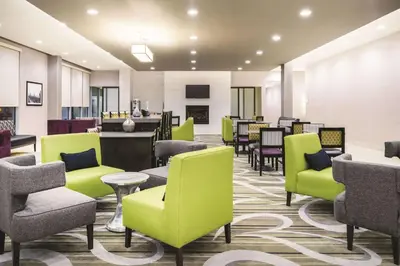 a waiting room with green chairs and tables at La Quinta Inn & Suites by Wyndham Clifton Park Saratoga Area 1749 Route 9 in Clifton Park