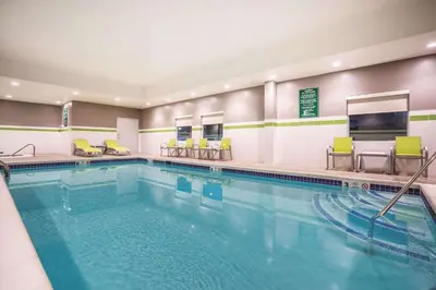 a pool in a hotel room with chairs at La Quinta Inn & Suites by Wyndham Clifton Park Saratoga Area 1749 Route 9 in Clifton Park
