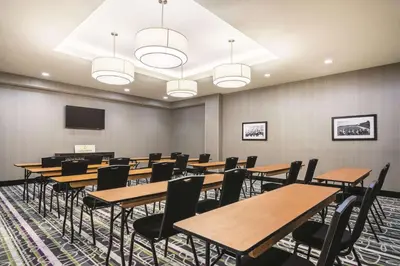 a conference room with tables and chairs and a screen at La Quinta Inn & Suites by Wyndham Clifton Park Saratoga Area 1749 Route 9 in Clifton Park