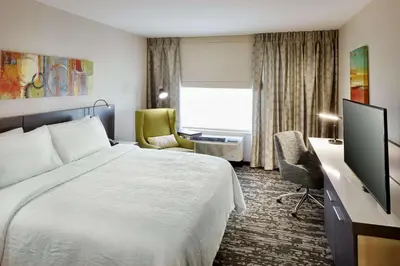 a hotel room with a bed and a desk with a television at Hilton Garden Inn Roslyn in Roslyn