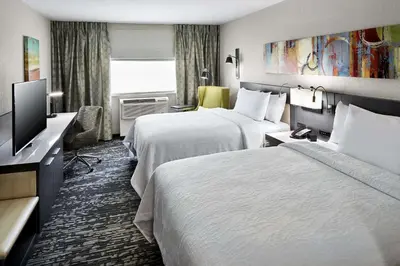 a hotel room with two beds and a flat screen tv at Hilton Garden Inn Roslyn in Roslyn