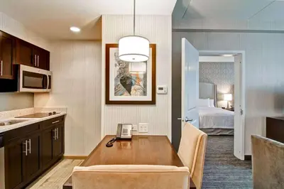 a kitchen with a table and a room with a bed at Homewood Suites By Hilton Clifton Park in Clifton Park