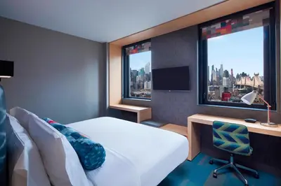 a bedroom with a bed and a desk and a window at Aloft Long Island City-Manhattan View in Queens