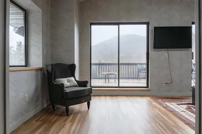 a living room with a chair and a large window at Hunter Lodge, a Bluebird by Lark in Hunter