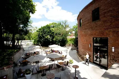 an outdoor restaurant with tables and umbrellas next to a brick building at The Roundhouse in Beacon