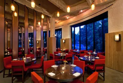 a restaurant with tables and red chairs and large windows at The Roundhouse in Beacon