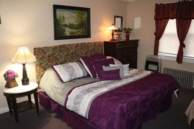 a bedroom with a bed with purple sheets and a lamp at Colonial Inn in Pine Hill