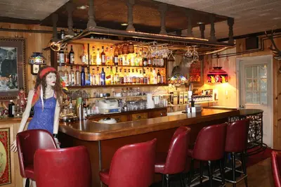 a woman standing in front of a bar with red chairs at Colonial Inn in Pine Hill