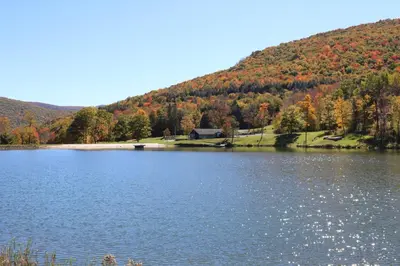 a lake in front of a mountain with fall foliage at Colonial Inn in Pine Hill