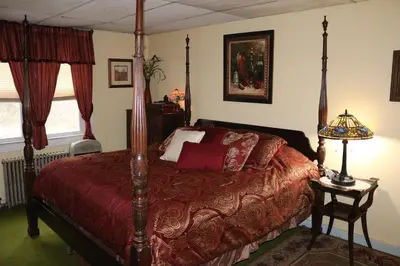 a bedroom with a bed with a red comforter at Colonial Inn in Pine Hill