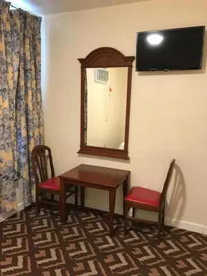 a room with a table and two chairs and a mirror at Waterbury Big Apple Motel in Waterbury