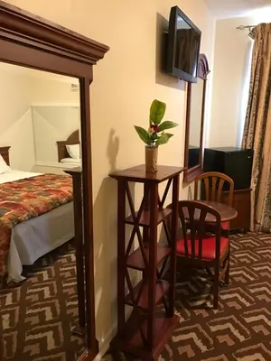 a hotel room with a bed and a table and a mirror at Waterbury Big Apple Motel in Waterbury